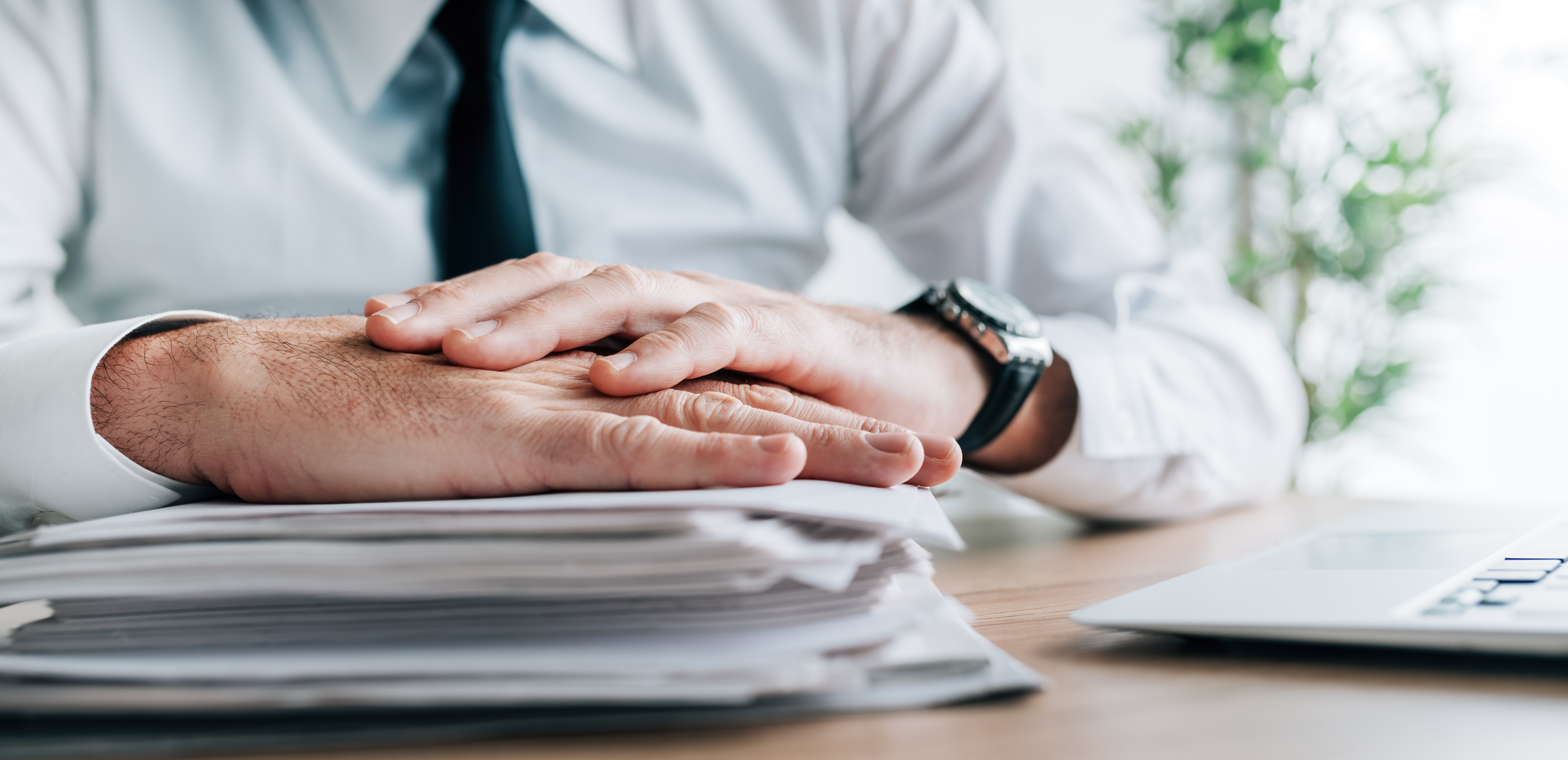Insurance agent with stack of policy contracts on office desk, panoramic image with selective focus